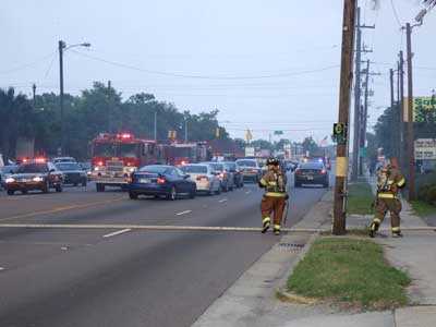 Fire fighters stretching a fire hose across a busy highway.