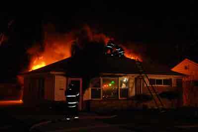 fire fighters on top of burning house