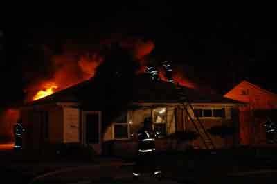 fire fighters, on top, on the side and in front of the house