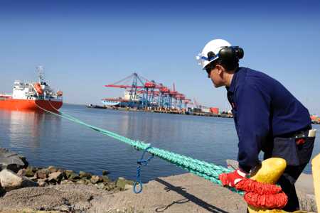 Dock worker secures mooring line to pile. 