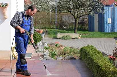 man pressure washing a patio