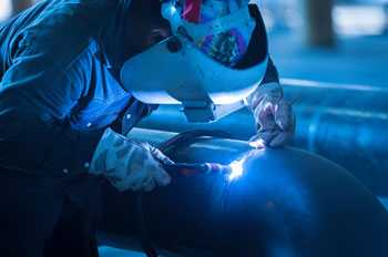 A welder hunches over his work surface