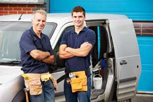 	Two construction workers standing outside of a truck