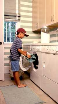 young boy doing laundry at home