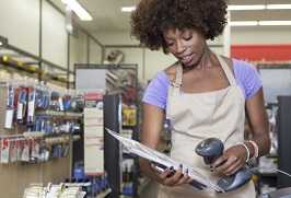 A young grocery worker scans an item in a grocery store.