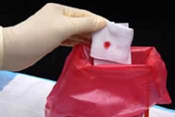 	gloved hand holding blood-stained gauze pad over disposal bag