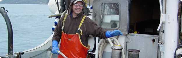 	A fisherman simulates the activation of the winch-mounted emergency stop system on the deck of the salmon purse seiner.