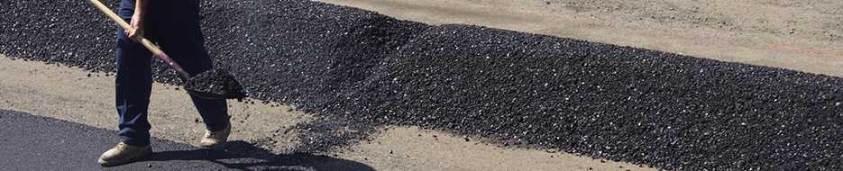 worker shoveling asphalt on highway