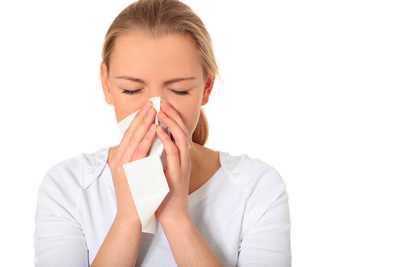 A woman sneezing into a tissue.