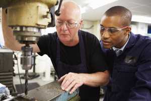 a machinist teaching techniques to a young worker