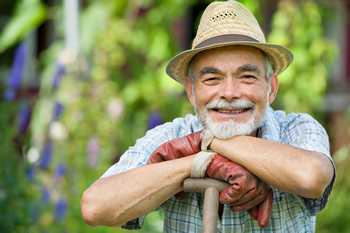 	A farmer leans on a tool and smiles.