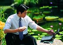 	a man eating his lunch outdoors while working on a laptop computer