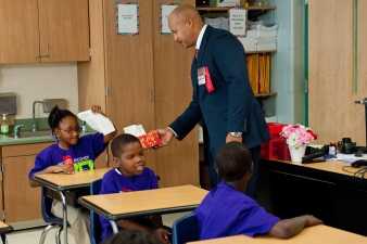 Teacher handing a student a tissue in a school classroom.