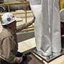 Eric Esswein of the CDC National Institute of Safety & Health (NIOSH) is shown next to the mini baghouse technology he designed to reduce worker exposure to silica dust at hydraulic fracturing sites. 