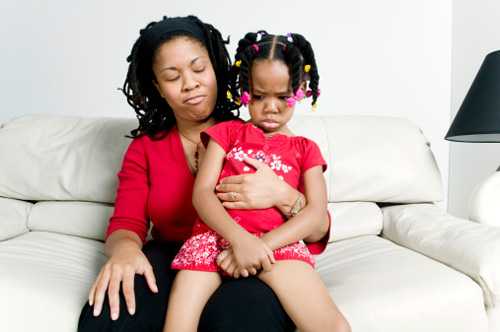 Toddler girl sitting in mom's lap pouting