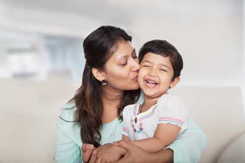 Mom kissing daughter