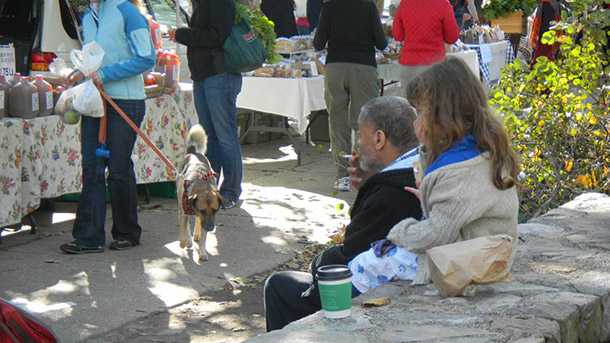 Man sitting outdoors smoking a cigarette while a child behind him covers her mouth and nose