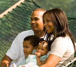 Mother and father with two children sitting outside.