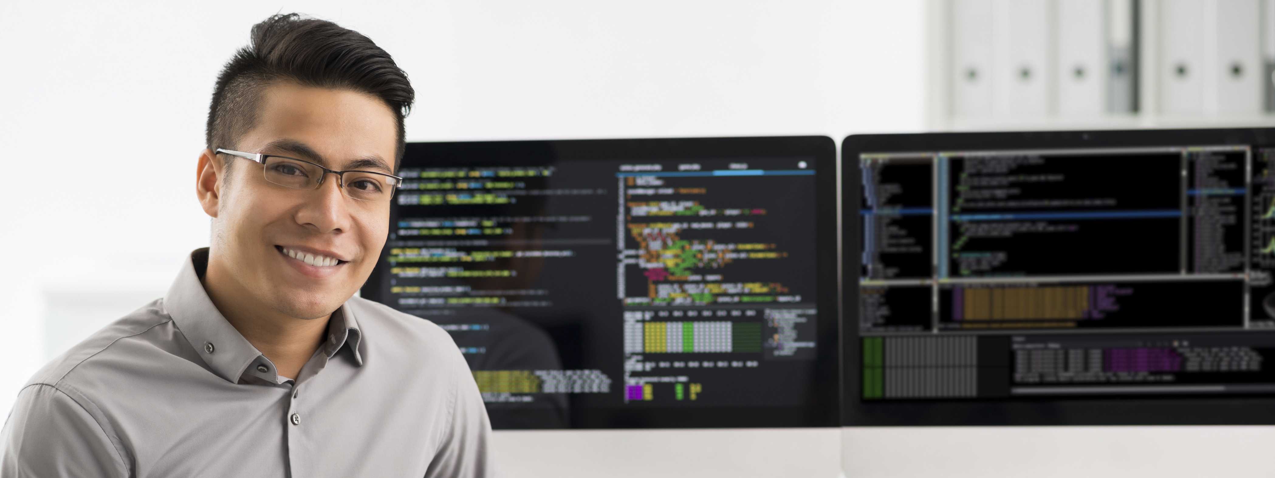 Male student looking with double monitors in the background.