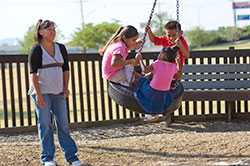 A woman and three children playing in a park