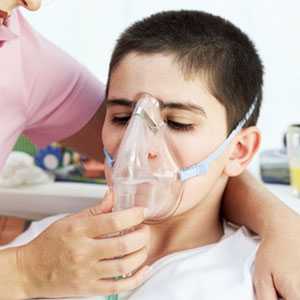 A young boy wears an oxygen mask while receiving a breathing treatment