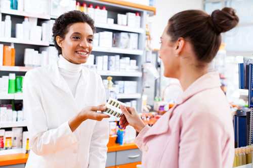 Pharmicist handing medications to woman.