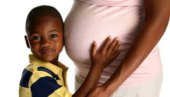 Pregnant woman with her son hugging her belly.