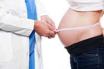 a doctor measuring a pregnant woman's belly.