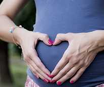 an image of a pregnant woman's hands formed in the shape of a heart over her belly