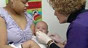 Nurse administering vaccine to a baby