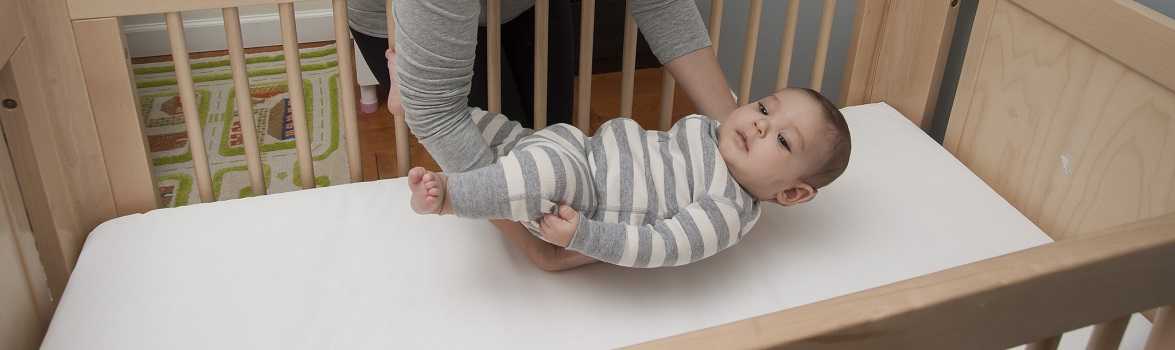 mother laying infant in crib