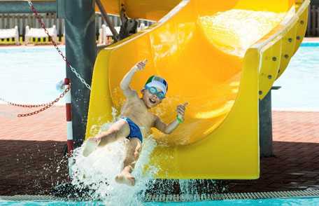 Niño en tobogán en la piscina