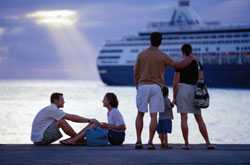 Gente en el muelle y un barco de cruceros en la distancia