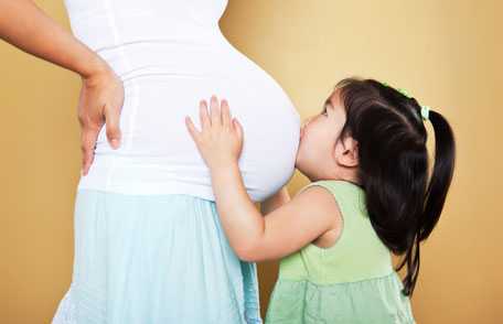 Niña besando el vientre de la madre embarazada