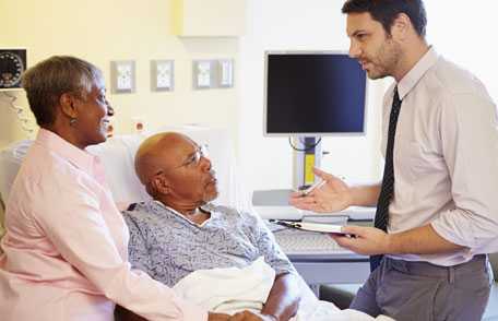 Un hombre hospitalizado y una mujer conversan con el médico.