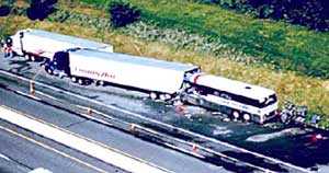 Fotografía de la escena de un siniestro en el que un autobús se salió de la carretera y entró en un "área de estacionamiento de emergencia", chocó con un camión con remolque y lo empujó contra un segundo camión con remolque.