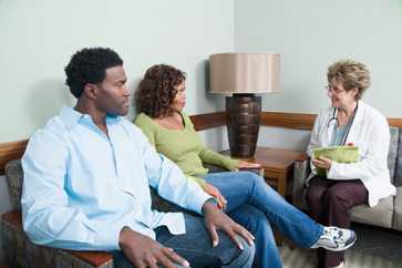 man and woman talking to a doctor