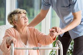 	Photo: older woman with a walker getting help 