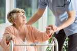 	photo: older woman with a walker getting help