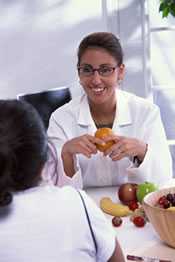 A smiling woman at work holding an orange