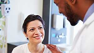 Male doctor talking with female, smiling patient