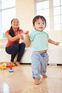 Mother encourages her walking baby