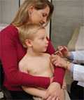 Mother holding child while getting vaccinated