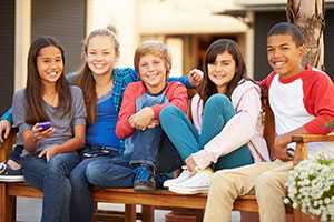 Group Of Children Sitting On Bench In Mall