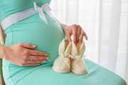 Pregnant woman holding baby boots