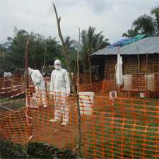 MSF (Medicins Sans Frontiers) health staff in protective clothing constructing perimeter for isolation ward.