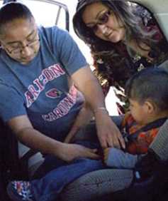 Grandmother buckling a toddler in a car seat